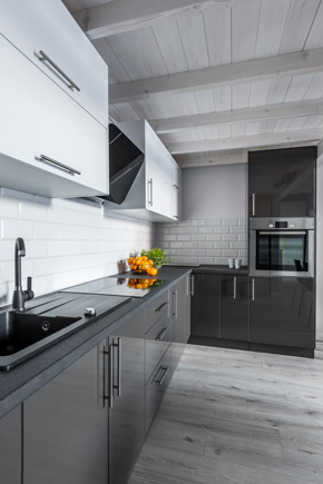 grey slate cupboards in modern kitchen with black chrome sink and oranges in fruit bowl on the side