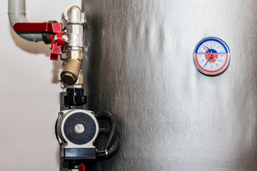 close up of silver hot water cylinder pipework and temperature gauge